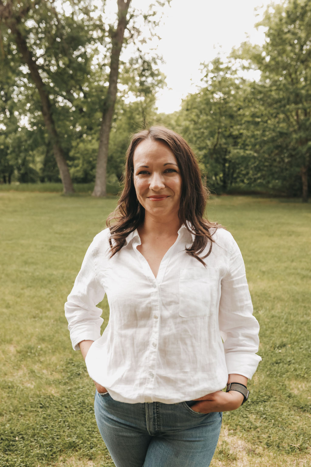 headshot of woman standing in forested area in summer