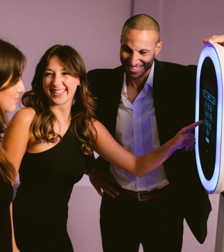 three people standing in front of a photo booth smiling and having a good time.